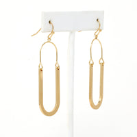 Oval shaped earrings featuring metal drops suspended from gold-plated hooks.