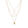 A modern triple-layered necklace in gold dangled with two bar charms.