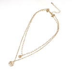 A two-layered paperclip chain necklace in gold dangled with two small charms.