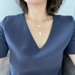 Wearing a two-layered paperclip chain necklace in gold dangled with two small charms.