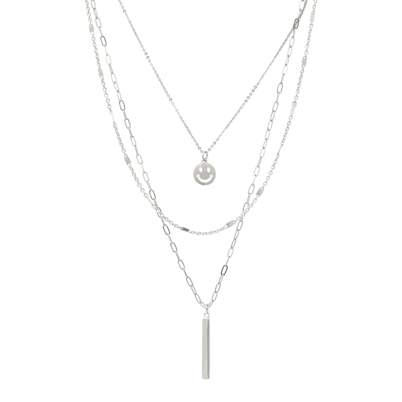 A set of triple layered necklace in silver with a small smiley face and a skinny bar charms.