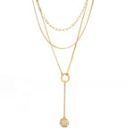 A modern triple layered necklace set in gold with a hammer textured charm.
