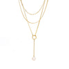 A modern triple layered necklace set in gold with a gold trimmed mother of pearl charm.