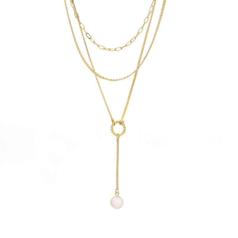 A modern triple layered necklace set in gold with a gold trimmed mother of pearl charm.