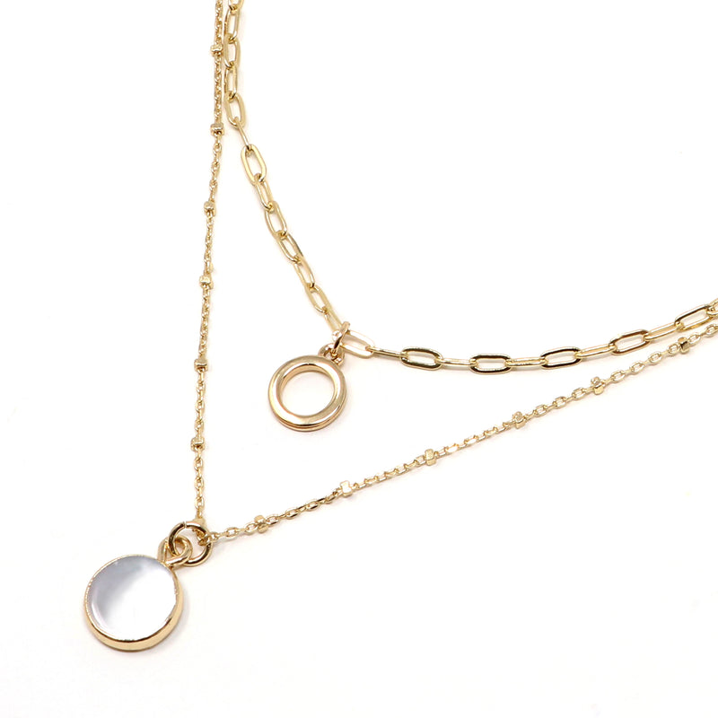 A set of two layer necklace in gold with a small disc and a gold trimmed mother of pearl charm.